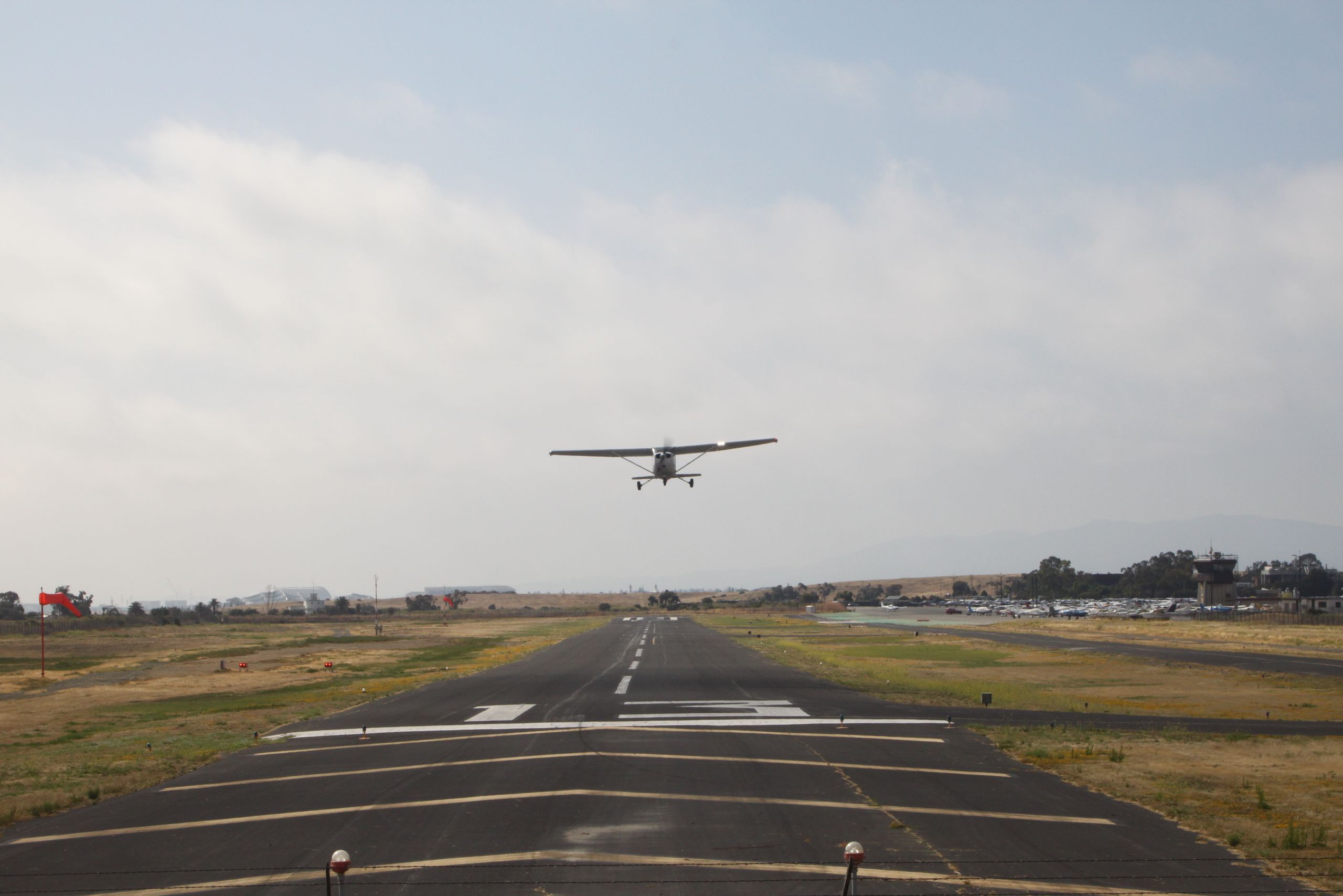 A small aircraft taking off on a cloudy day from an airport runway.