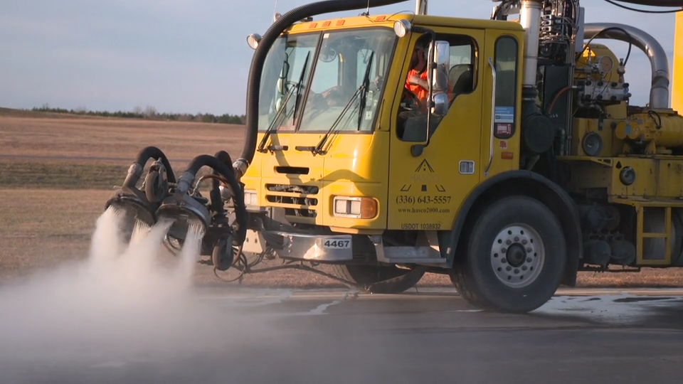Yellow airport runway sweeper or maintenance vehicle.