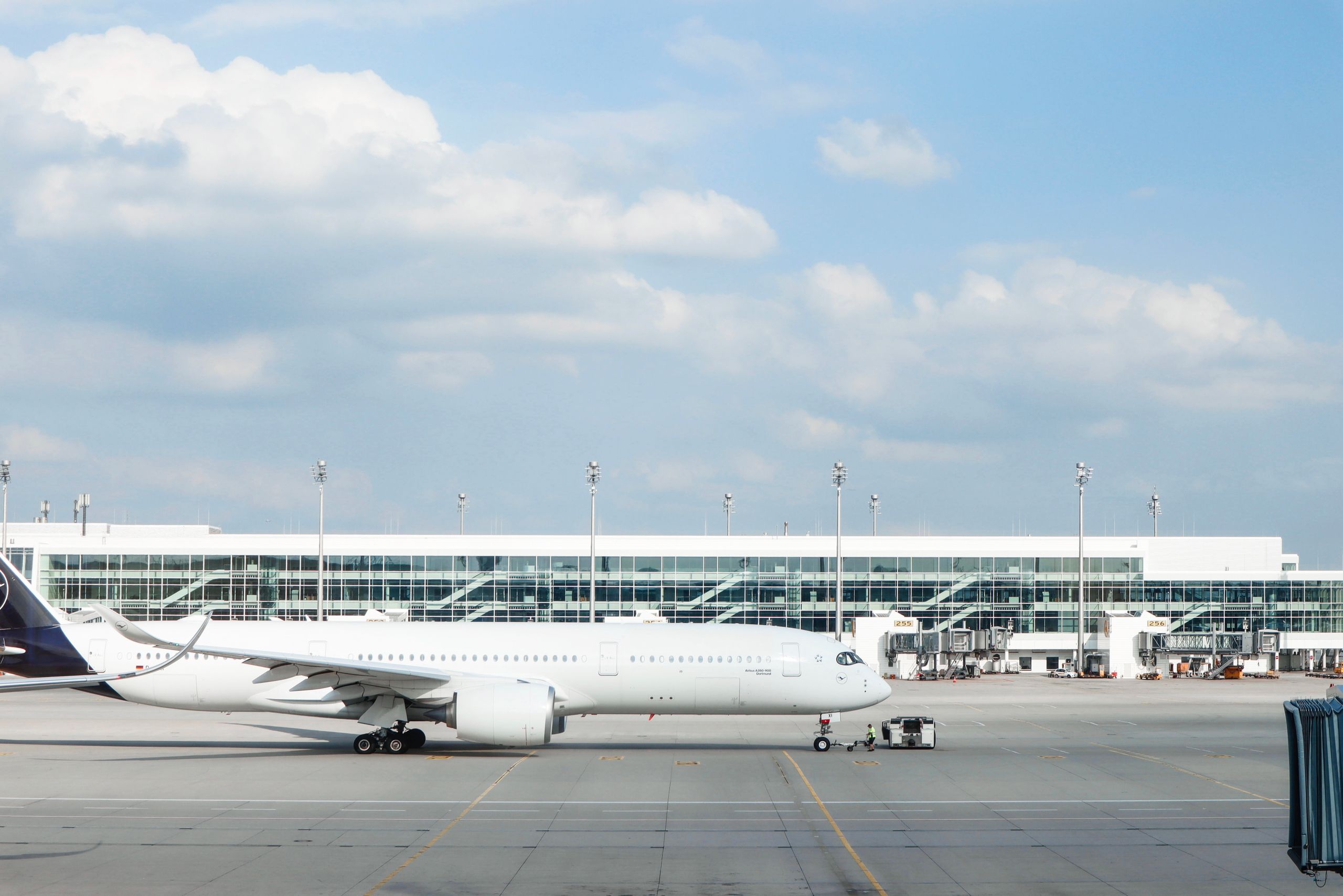 Widebody aircraft parked at an airport gate during clear day with terminal building visible.